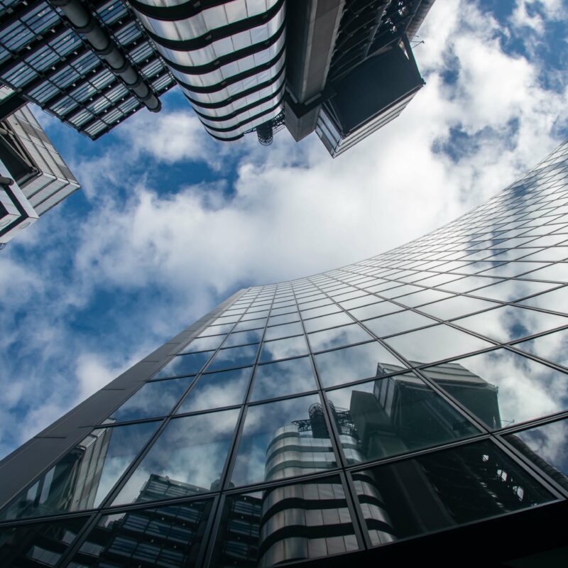 Worms eye view of glass building under blue and white sunny cloudy sky during daytime